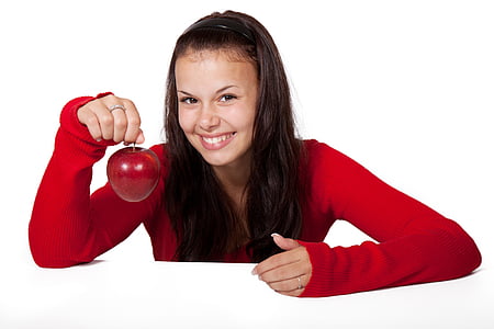 girl in red sweater smiling and holding an apple