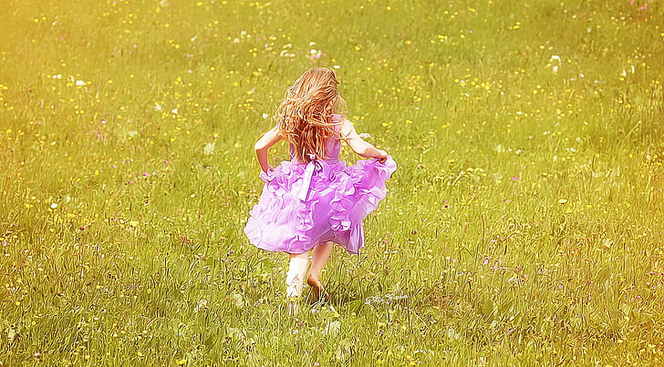 girl wearing pink dress running on grass field