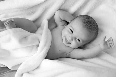baby lying on white textile