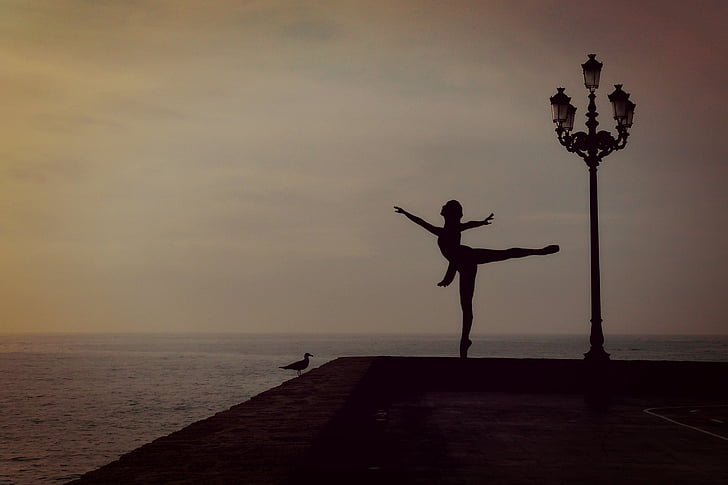 silhouette of woman perform ballerina beside street lamp