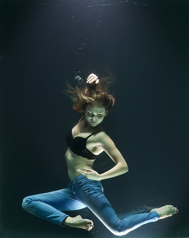 woman in black bra and blue denim jeans sinking in water