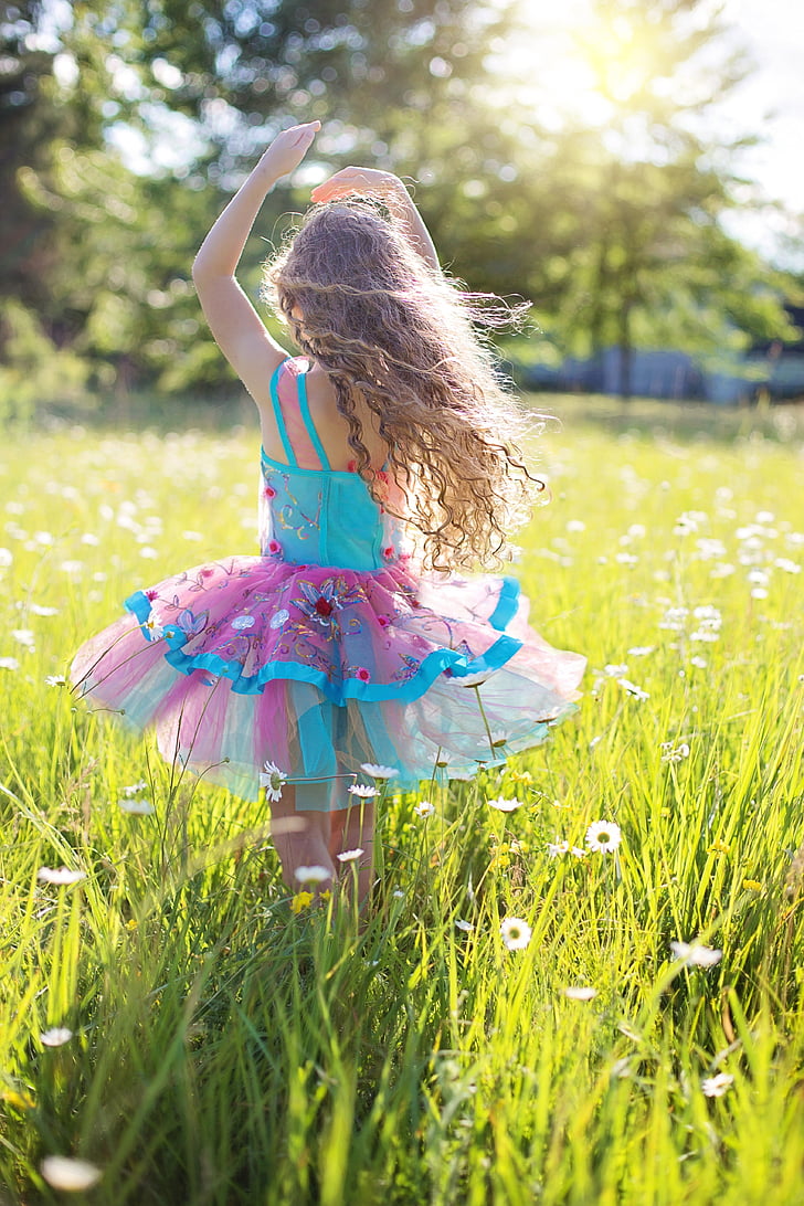 girl wearing blue and pink dress in the middle of white flower field