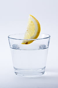 photo of lemon about to drop on glass of water