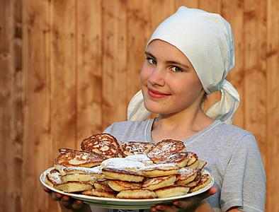 woman wearing gray scoop-neck t-shirt carrying pancake with powdered sugar on top