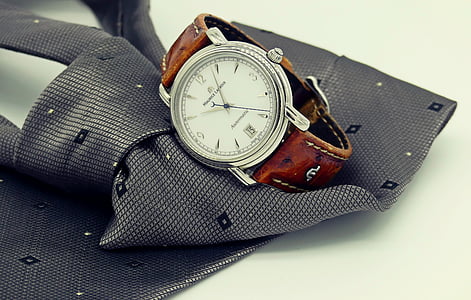 round silver-colored bezel analog watch on top of gray necktie