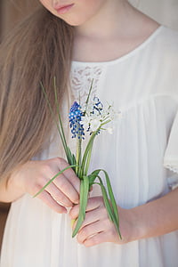 woman in white holding blue and white flowers