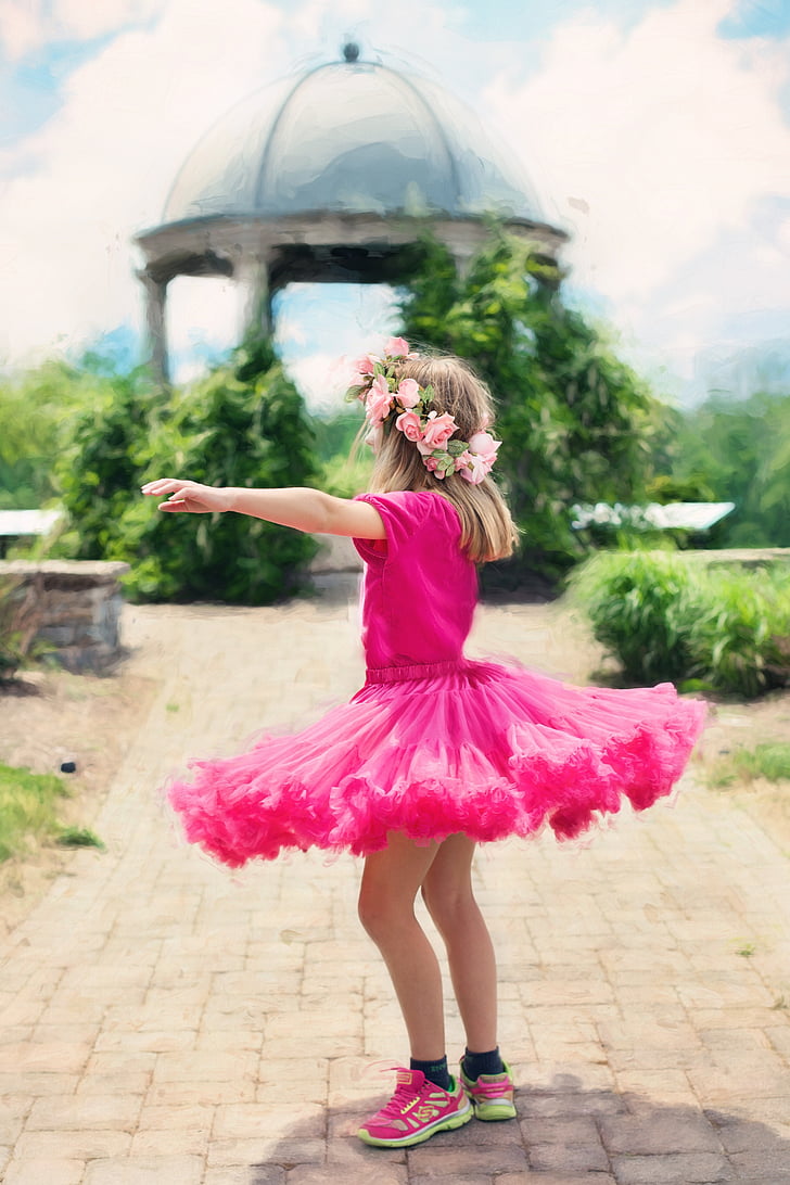 girl wearing pink tutu dress standing facing on green leaf plant selective focus photograph