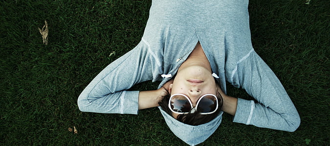 person lying on green grass wearing sunglasses