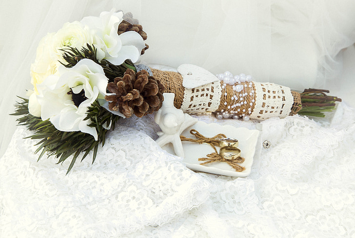 white flowers with pine cones bouquet and pair of gold-colored earrings