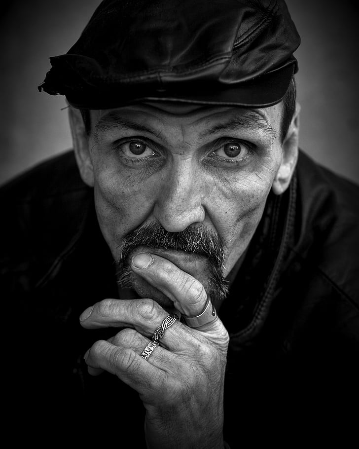 grayscale photo of man with leather flat cap