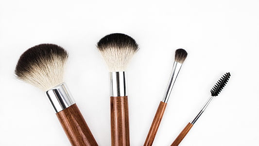 four brown makeup brushes with white background