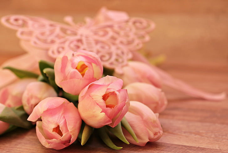 selective focus photo o fpink tulips bouquet on brown wooden surface