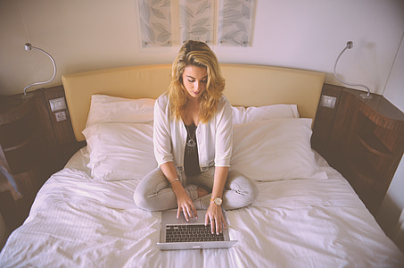 woman sitting on bed touching laptop