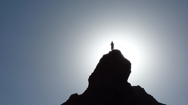 silhouette person standing on peak of mountain