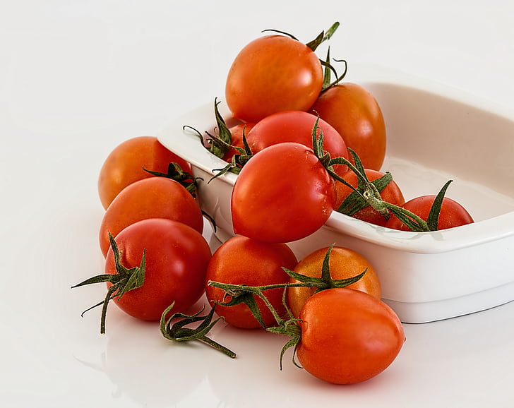 bunch of tomatoes on and white bowl