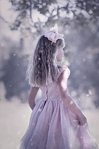 girl wearing pink dress standing while snow falling