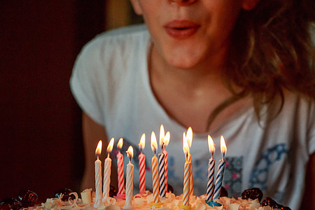 woman wearin ggray printed shirt blowing candle in cake