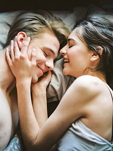 man and woman in white top laying on bed