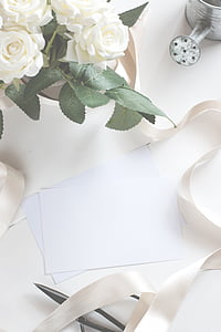 white papers on table beside white petaled flowers
