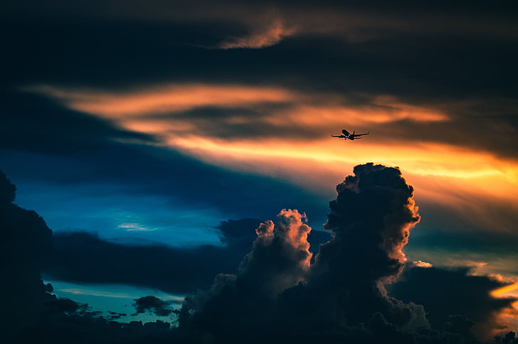 silhouette photo of plane near clouds