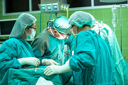 four medical staff with wearing medical gowns while doing surgery