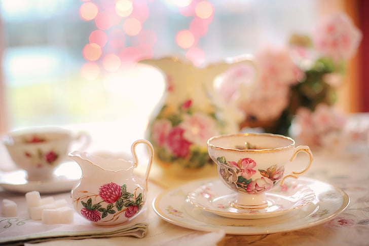 selective focus photography of white and pink floral ceramic cup and saucer