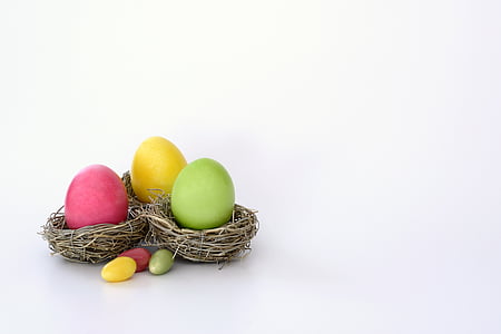 pink, yellow, and green Easter egg on brown nest