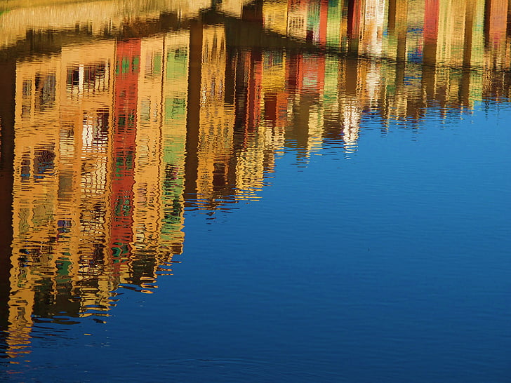 assorted-color building reflecting on body of water at daytime