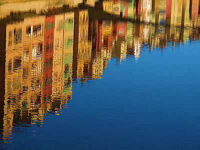 assorted-color building reflecting on body of water at daytime