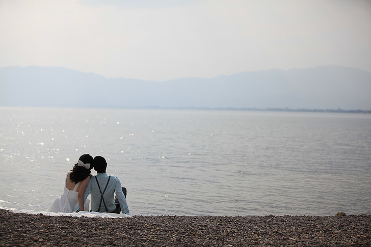 couple sitting on seashore during daytime
