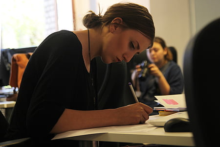 woman holding pen while writing