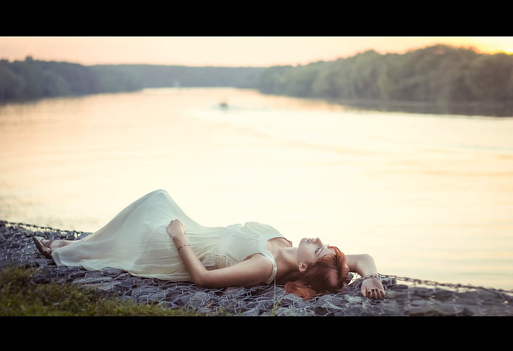 Royalty-Free photo: Selective focus photography of woman laying on ground  near body of water wearing white sleeveless long dress | PickPik