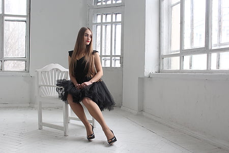 woman in black dress sitting on armchair inside room
