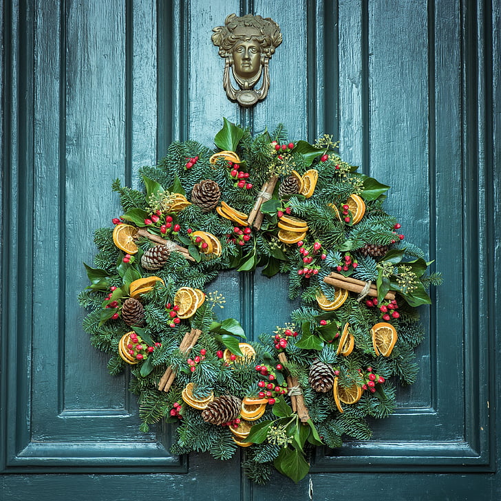 green, yellow, and red floral wreath hanging on grey wooden door