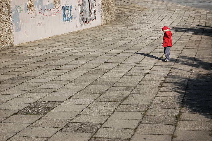 boy standing on pavement during daytime
