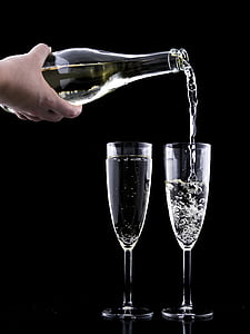 person pouring champagne on two glasses