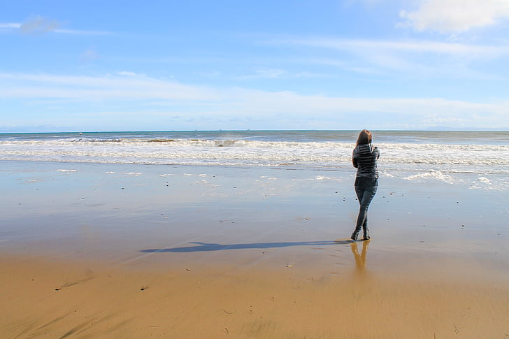woman standing on shoreline facing back