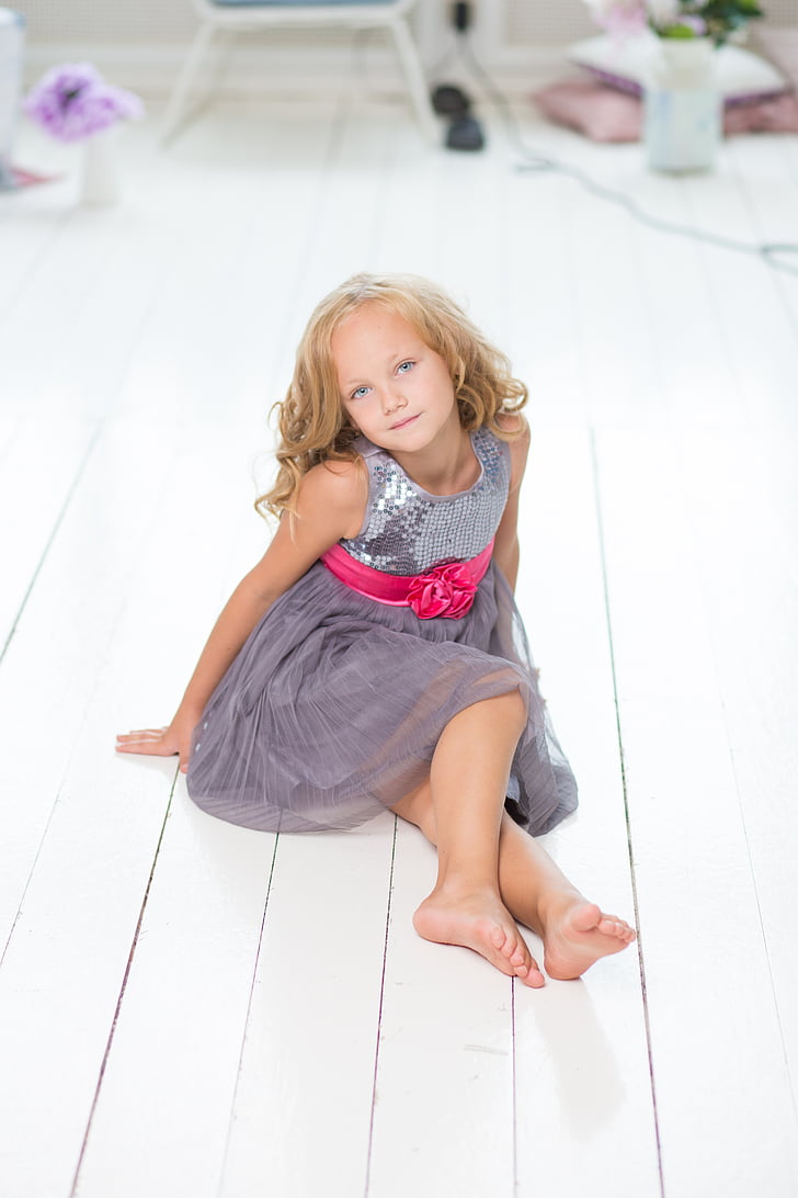 girl in gray dress sitting on white wooden floor