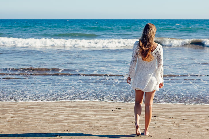 woman walking towards beach shore