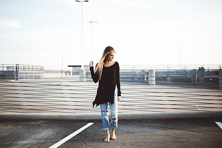 woman wearing black long-sleeved shirt standing on grey concrete road