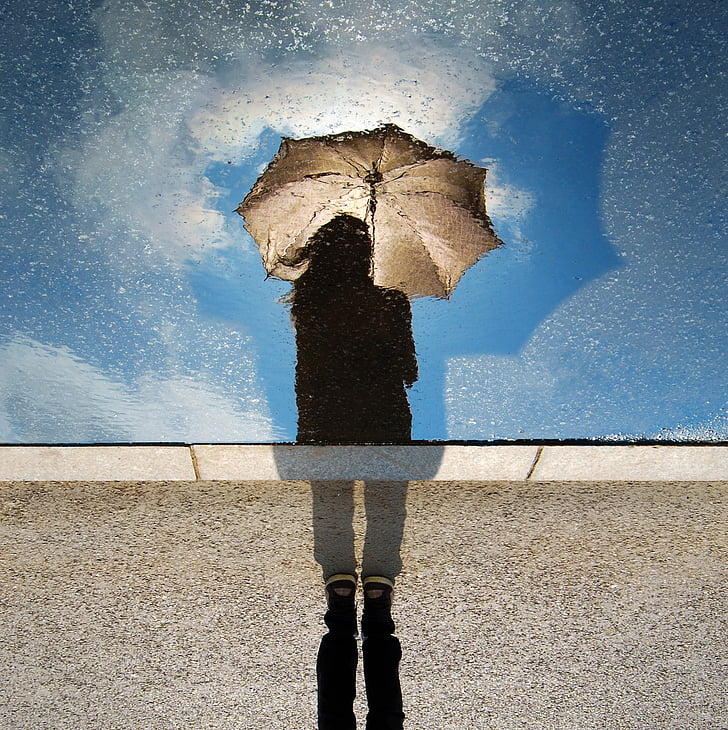 silhouette of woman with brown umbrella under bright sky