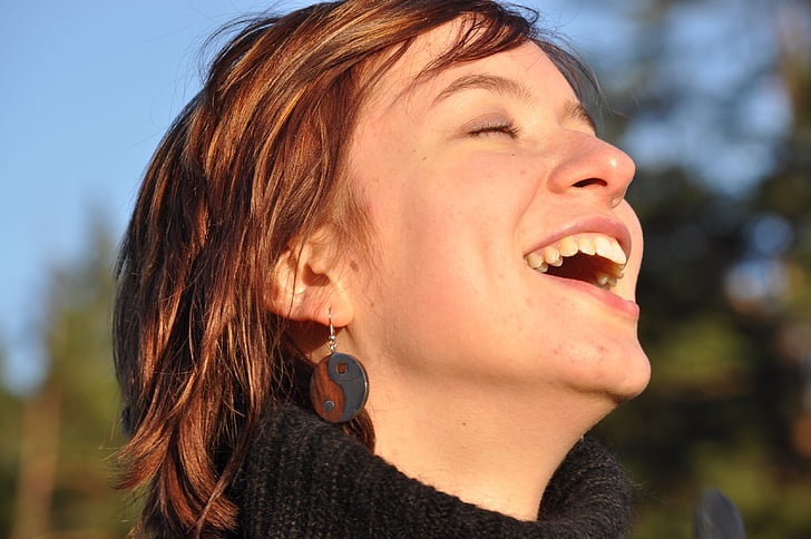 woman in black sweater laughing with eyes close