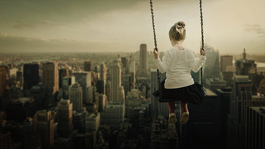 girl sitting on swing with overlooking skycrapers