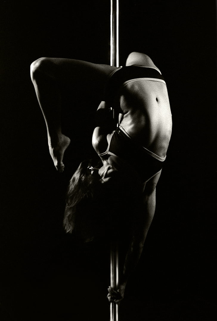 grayscale photograph of woman dancing on pole