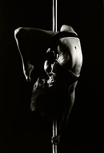 grayscale photograph of woman dancing on pole