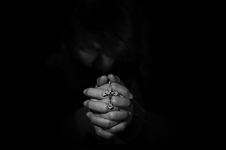 closeup grayscale photography of person's hand holding rosary
