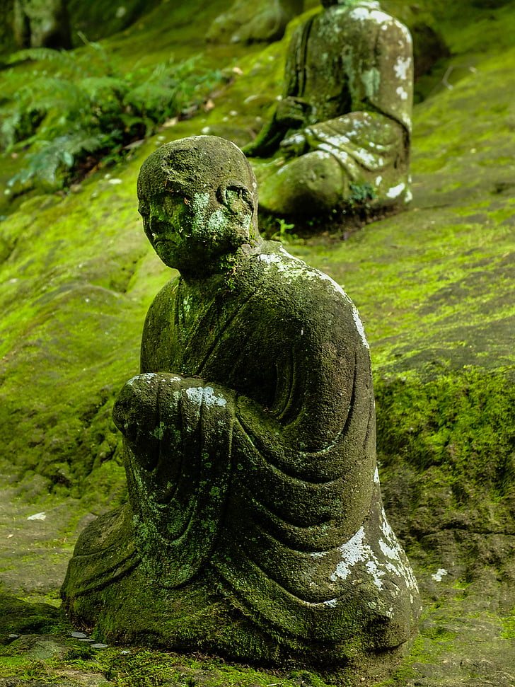 sitting monk statue with algae during daytime
