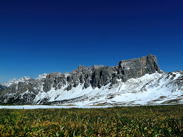 landscape photo of green grass field near rock mountain