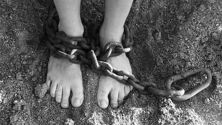 grayscale photography of person with chain on both feet