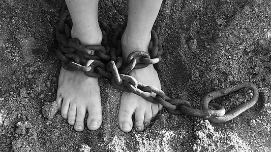 grayscale photography of person with chain on both feet